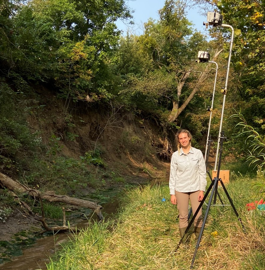 Gretchen standing next to sprinklers used in her experiment during summer 2020 in Kings Creek.